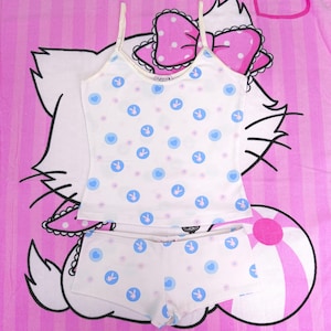 May include: White camisole and shorts set patterned with blue Playboy bunny logos and hearts. The set has thin straps and trim. The background is a pink and white striped pattern with a cartoon cat.
