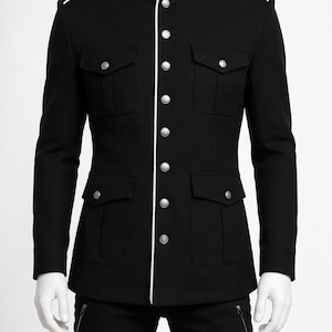 May include: Black military-style jacket with a mandarin collar and white trim. The jacket features silver buttons, four front pockets, and epaulets. The jacket is displayed on a mannequin.
