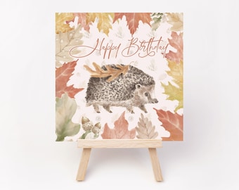 May include: A printable birthday card featuring a hedgehog carrying a leaf, surrounded by autumn leaves. The card says "Happy Birthday".