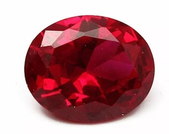 May include: A vibrant, deep red gemstone cut into an oval shape with multiple facets. The stone displays a high level of clarity and brilliance, reflecting light across its polished surface. The intense crimson color is consistent throughout the gem.