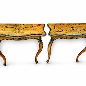 Può includere: Due consolle antiche dipinte a mano. I tavoli hanno un design curvo con gambe dorate ornate. Il piano del tavolo è giallo chiaro con disegni floreali e a volute in rosso, blu e verde. Ogni tavolo misura circa 76 cm di lunghezza.