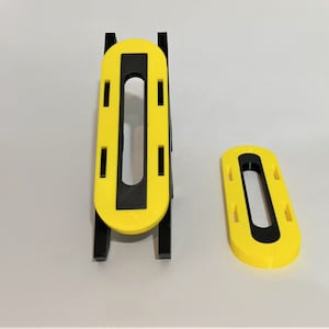 May include: Two yellow plastic stands with black accents. The stands have a rectangular shape with a cutout in the center. The stands are designed to hold items upright.