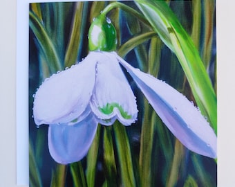 May include: A greeting card featuring a detailed painting of a snowdrop flower. The white petals have a hint of purple and are accented with green. Water droplets are visible on the flower. The background shows green blades of grass.