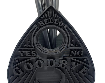 May include: Black plastic Ouija board-shaped makeup brush holder with the words "HELLO", "YES", "NO", and "GOODBYE" inscribed on it.