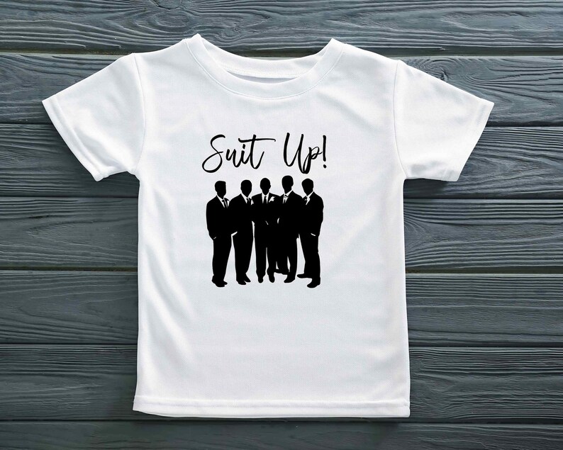 K&ouml;nnte beinhalten: Wei&szlig;es T-Shirt mit einer schwarzen Silhouette von sechs M&auml;nnern im Anzug und dem Text "Suit Up!" auf der Vorderseite.
