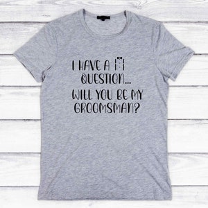 K&ouml;nnte beinhalten: Graues T-Shirt mit schwarzem Text, der lautet: "Ich habe eine Frage... Willst du mein Trauzeuge sein?"