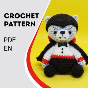 May include: A crocheted bear dressed as a vampire, with a black cape, bow tie, and red accents. The bear has gray fur, a white face, and is sitting on a yellow background. Text on the left reads "CROCHET PATTERN PDF EN".