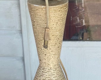 May include: A mid-century modern table lamp with a white, brown, and orange ceramic base. The lamp has a geometric design and a gold-colored metal base.