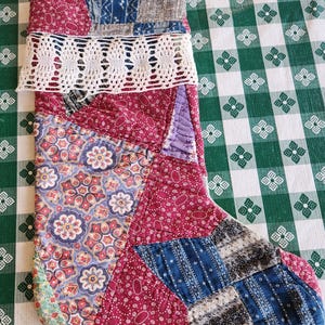May include: A red, blue, and white patchwork Christmas stocking with a white crocheted trim.