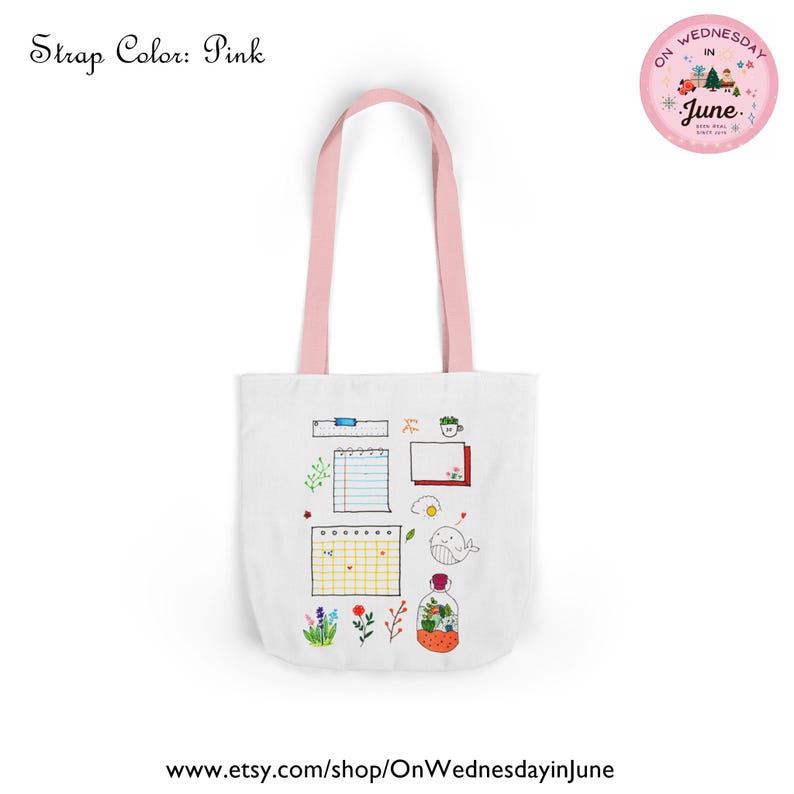 Puede incluir: Bolso tote blanco con correas rosas. Presenta ilustraciones coloridas dibujadas a mano de un calendario, una ballena, flores y elementos de papeler&iacute;a. El texto "On Wednesday in June" est&aacute; en un c&iacute;rculo rosa.