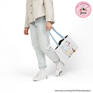 Puede incluir: Bolso tote blanco con asas azul claro con ilustraciones coloridas de calendarios, notas y plantas. El bolso lo lleva una persona con vaqueros de lavado claro y zapatillas blancas. Un logotipo circular rosa est&aacute; en la esquina superior derecha.