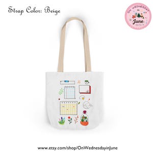 Puede incluir: Bolso tote blanco con correas beige. Presenta un dise&ntilde;o caprichoso de ilustraciones estilo cuaderno, incluyendo un calendario, una ballena y un terrario. El texto "Strap Color: Beige" est&aacute; en la parte superior izquierda. El logo de la tienda est&aacute; arriba a la derecha.