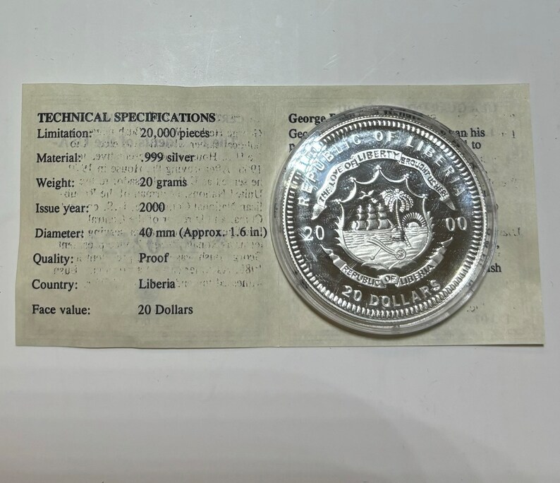 May include: A silver proof coin from Liberia, featuring the country's coat of arms with a ship and palm trees. The coin is dated 2000 and has a face value of 20 Dollars. The coin is displayed in a plastic case with a white card that lists technical specifications.