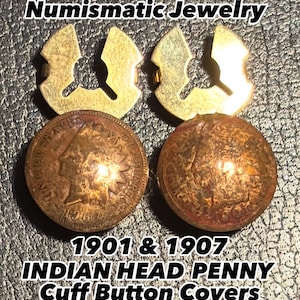 May include: Numismatic jewelry featuring two Indian Head penny cuff button covers. The cuff button covers are gold-colored and shaped like a stylized arrow. The pennies are dated 1901 and 1907.