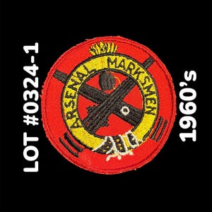May include: Embroidered patch with a red circular design featuring the words "ARSENAL MARKSMEN" in yellow, with crossed black rifles at the center. The text "1960's" and "LOT #0324-1" are also visible.