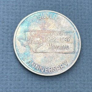 May include: Silver coin commemorating the 25th anniversary of a celebration on the bayou, 1962-1987, Monsanto.