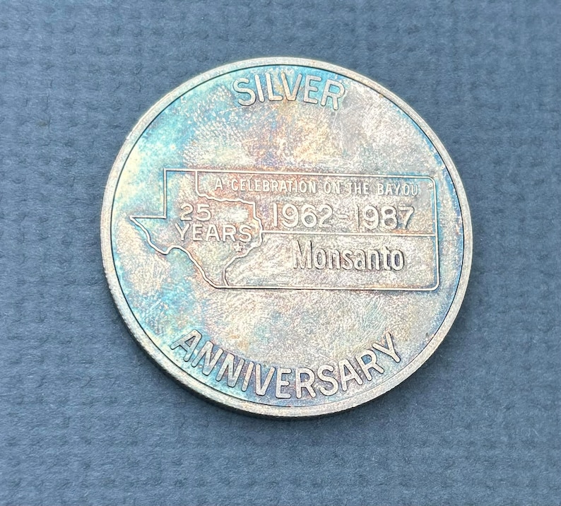 May include: Silver coin commemorating the 25th anniversary of a celebration on the bayou, 1962-1987, Monsanto.