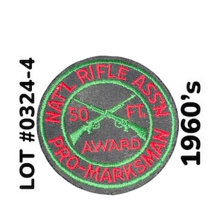 May include: A green and red embroidered patch with the text "NAT'L RIFLE ASS'N PRO-MARKSMAN 50 FT AWARD" in a circle. The patch is from the 1960s.