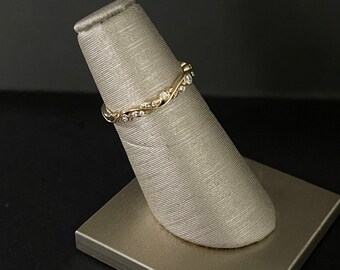 May include: A delicate gold band ring with a twisted design and small clear diamonds set in the metal.