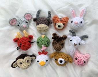 May include: Twelve crocheted animal plushies representing the Chinese zodiac signs. The plushies are in various colors, including red, white, brown, green, and pink.