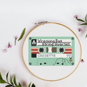 Puede incluir: Un patrón de punto de cruz verde y blanco de una cinta de casete con el texto "Wrecking Ball String Quartet" y "CASSETTE 90".