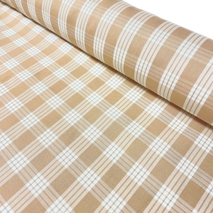 May include: A roll of fabric featuring a plaid pattern in tan and white. The fabric is tightly woven, with a repeating grid of intersecting lines. The pattern is a classic design, suitable for various sewing projects.