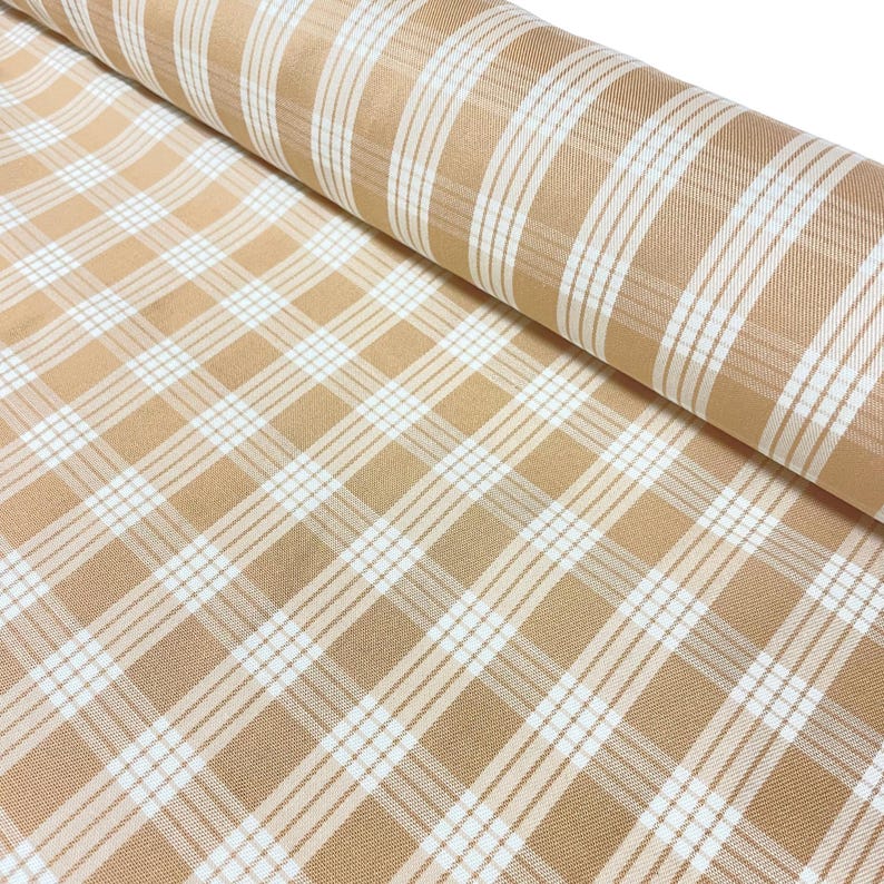 May include: A roll of fabric featuring a plaid pattern in tan and white. The fabric is tightly woven, with a repeating grid of intersecting lines. The pattern is a classic design, suitable for various sewing projects.