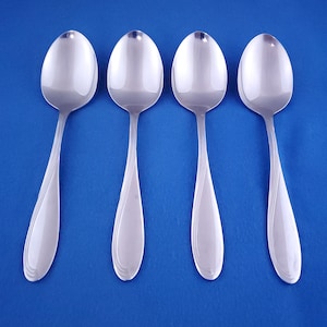 May include: Four silver spoons with a rounded bowl and a slightly curved handle.