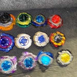 Puede incluir: Una colecci&oacute;n de peonzas coloridas en varios dise&ntilde;os. Las peonzas presentan una mezcla de colores, incluyendo rojo, azul, amarillo, verde y morado. Cada peonza tiene un dise&ntilde;o &uacute;nico con m&uacute;ltiples capas y texturas.