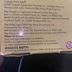 Pu&ograve; includere: Una scatola di cartone color marrone chiaro con i loghi Play Along e JAKKS Pacific. Il testo include Cabbage Patch Kids, copyright 2005, dettagli di produzione e una nota per gli adulti di rimuovere le chiusure in plastica prima dell'uso.
