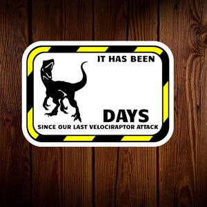 May include: A yellow and black warning sign with a silhouette of a velociraptor and the text "It has been DAYS since our last velociraptor attack."