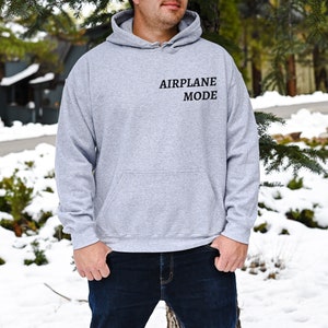 Puede incluir: Una sudadera con capucha gris con el texto "AIRPLANE MODE" impreso en la parte delantera.
