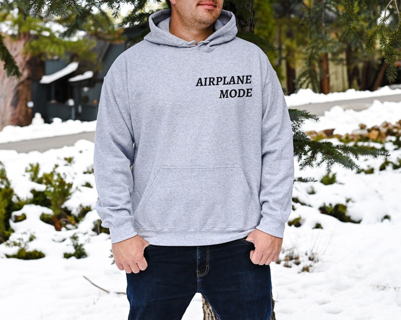 Puede incluir: Una sudadera con capucha gris con el texto "AIRPLANE MODE" impreso en la parte delantera.
