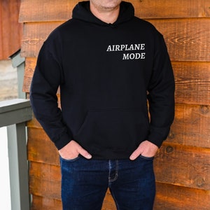 Puede incluir: Una sudadera con capucha negra con el texto "AIRPLANE MODE" impreso en blanco en la parte delantera.