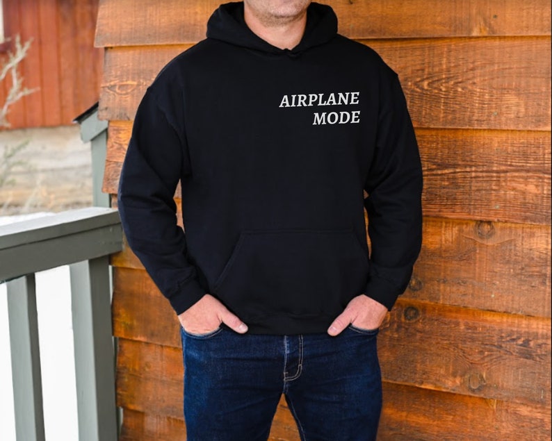 Puede incluir: Una sudadera con capucha negra con el texto "AIRPLANE MODE" impreso en blanco en la parte delantera.