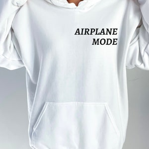 Puede incluir: Sudadera con capucha blanca con el texto "AIRPLANE MODE" impreso en la parte delantera.