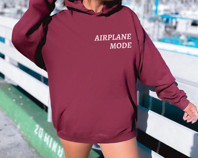 Puede incluir: Una sudadera con capucha color burdeos con un gr&aacute;fico bordado en blanco que dice "MODO AVI&Oacute;N".