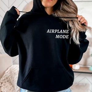 Puede incluir: Sudadera con capucha negra con el texto "AIRPLANE MODE" en letras blancas.
