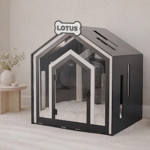 May include: A dark gray and white pet house with a gabled roof and a clear front door. The structure features a bone-shaped sign at the peak with the text LOTUS printed in black. Inside, a white cushioned bed is visible through the transparent door.