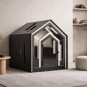 May include: A black pet house with a gabled roof, featuring a light-colored wood trim around the front entrance and a glass door with a black handle. The structure has rectangular side cutouts and a slanted roof design with two narrow openings.