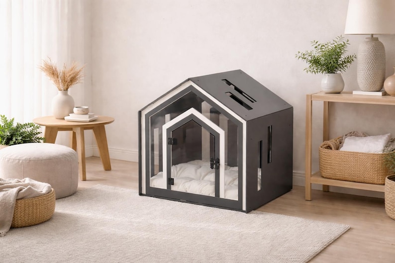 May include: A dark gray pet house with a gabled roof design, featuring a clear acrylic front panel with a white-trimmed door frame. The structure includes vertical side cutouts and contains a plush, tufted white cushion inside for comfort.