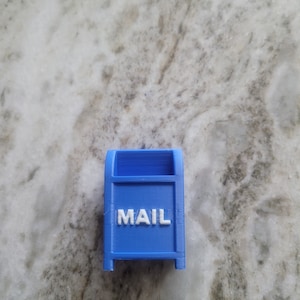 May include: A small blue plastic mailbox with the word "MAIL" printed in white on the front.