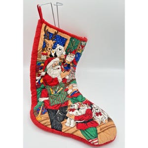 Peut inclure: Une chaussette de Noël matelassée avec un imprimé festif coloré représentant le Père Noël, des rennes, des ours en peluche et des lutins. La chaussette possède une bordure en tissu rouge vif et une boucle de suspension sur le dessus.