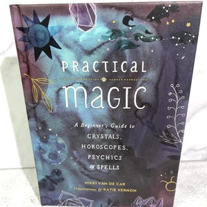 May include: A book titled "Practical Magic: A Beginner's Guide to Crystals, Horoscopes, Psychics & Spells" by Nikki Van de Car with illustrations by Katie Vernon. The cover features a watercolour design with stars, moons, and crystals on a dark blue and purple background.