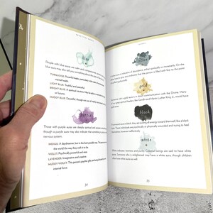 May include: A book page with a chart of different aura colours and their meanings. The colours include blue, turquoise, light blue, bright blue, muddy blue, purple, indigo, violet, lavender, muddy violet, silver, gold, black, and white. The text describes the characteristics of people with each aura colour.