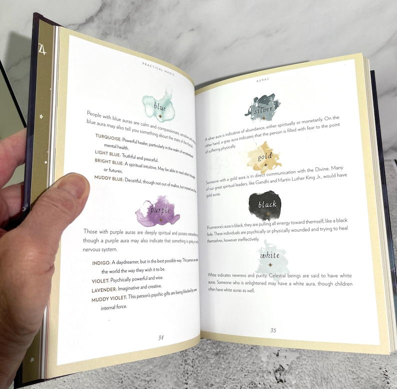 May include: A book page with a chart of different aura colours and their meanings. The colours include blue, turquoise, light blue, bright blue, muddy blue, purple, indigo, violet, lavender, muddy violet, silver, gold, black, and white. The text describes the characteristics of people with each aura colour.