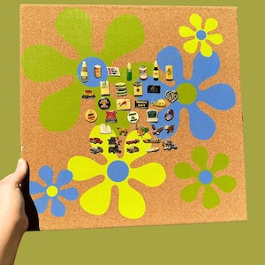 May include: A corkboard decorated with large, retro-style flowers in green, blue, and yellow. The board is covered with vintage-themed magnets, including miniature cars, food labels, and other novelty items. The text "TOTALLY HOT" is visible.