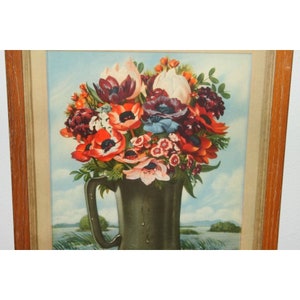 May include: A framed vintage print of a still life featuring a bouquet of red, white, and pink flowers in a green ceramic pitcher. The flowers are arranged in a vase with a blue and white background.