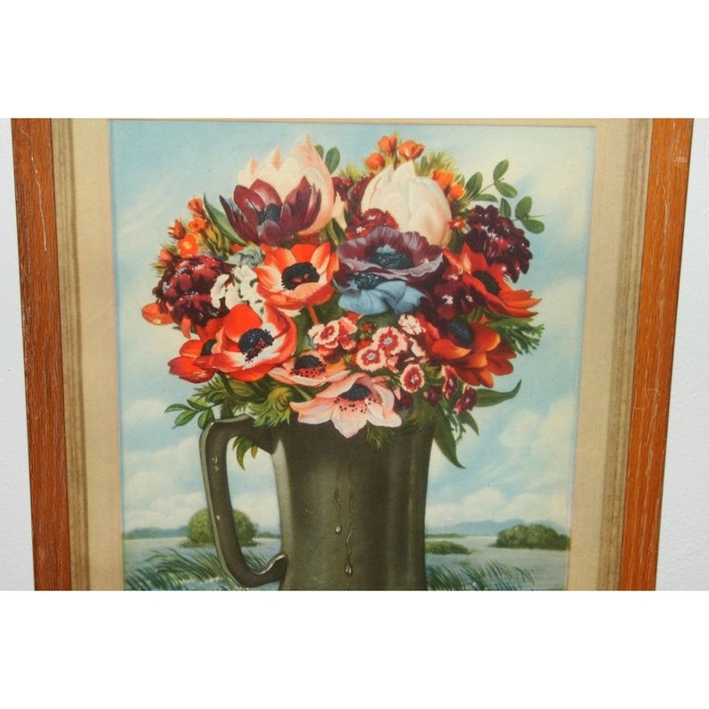 May include: A framed vintage print of a still life featuring a bouquet of red, white, and pink flowers in a green ceramic pitcher. The flowers are arranged in a vase with a blue and white background.