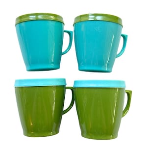 May include: Four vintage plastic mugs with lids. Two are teal with green lids, and two are green with light blue lids. Each mug has a handle and a slightly flared shape.